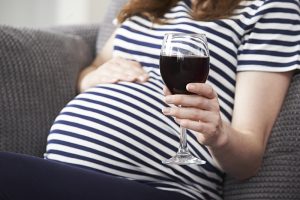 Kobieta w ciąży z lampką wina Centrum diagnozy i terapii ENGRAM w Kielcach